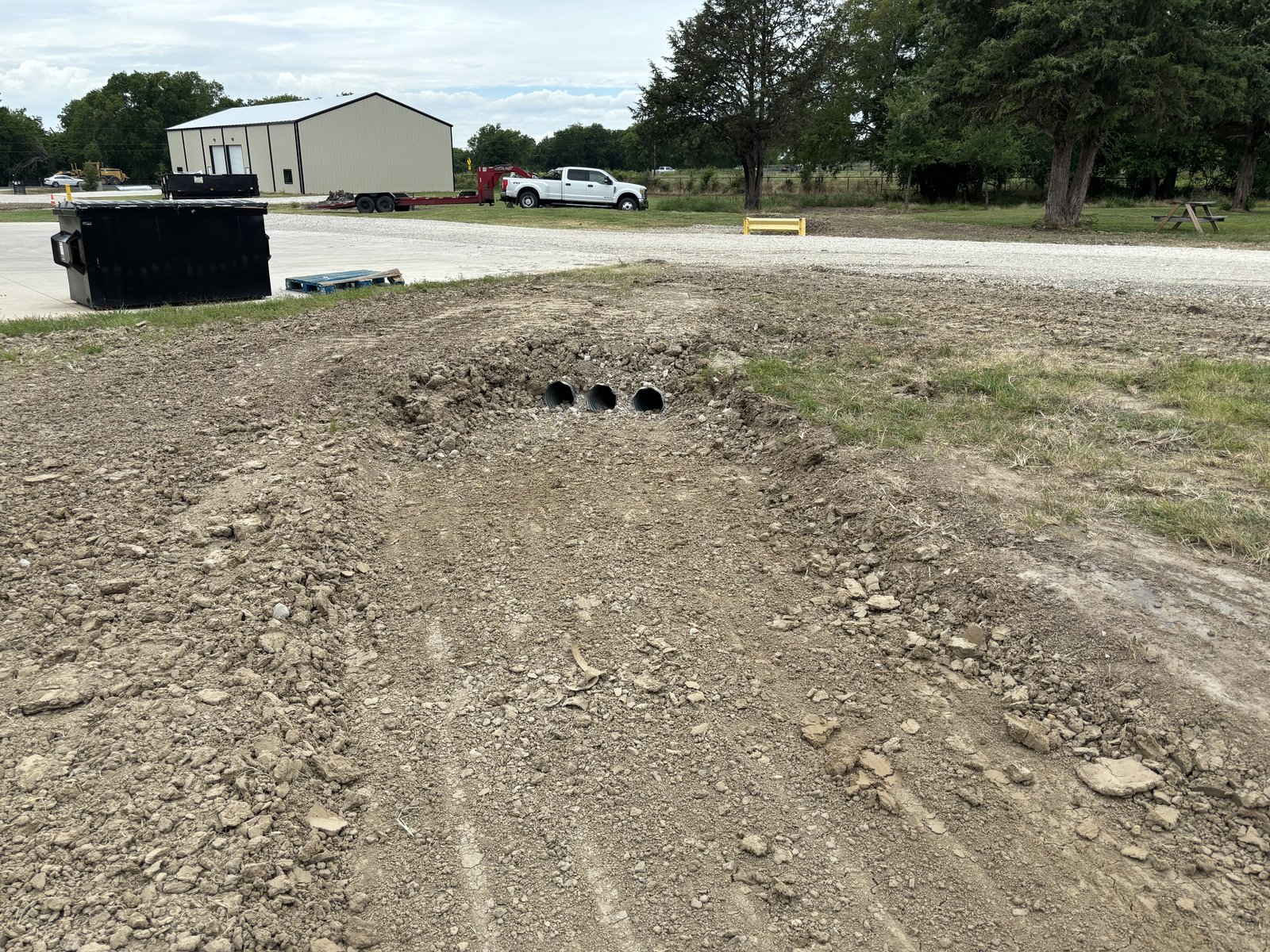 Three black culvert pipes installed in a graded drainage crossing