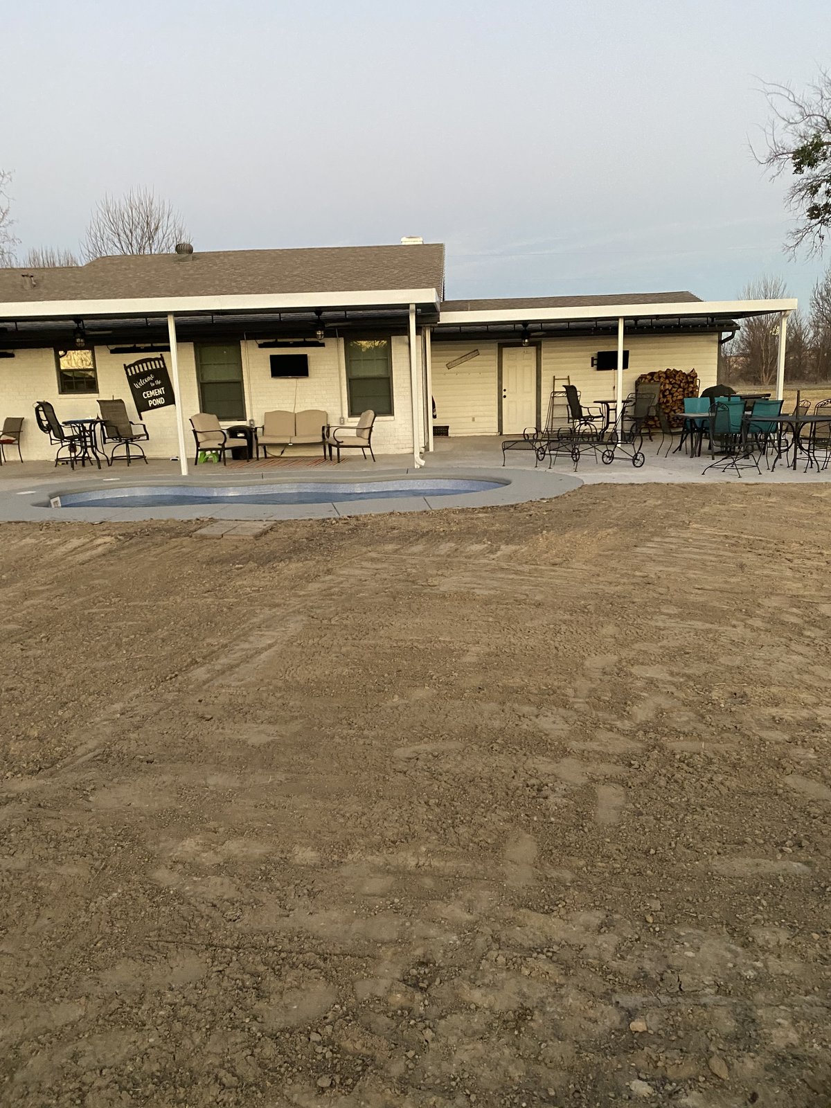 Freshly graded dirt in a backyard leading to a small pool and patio