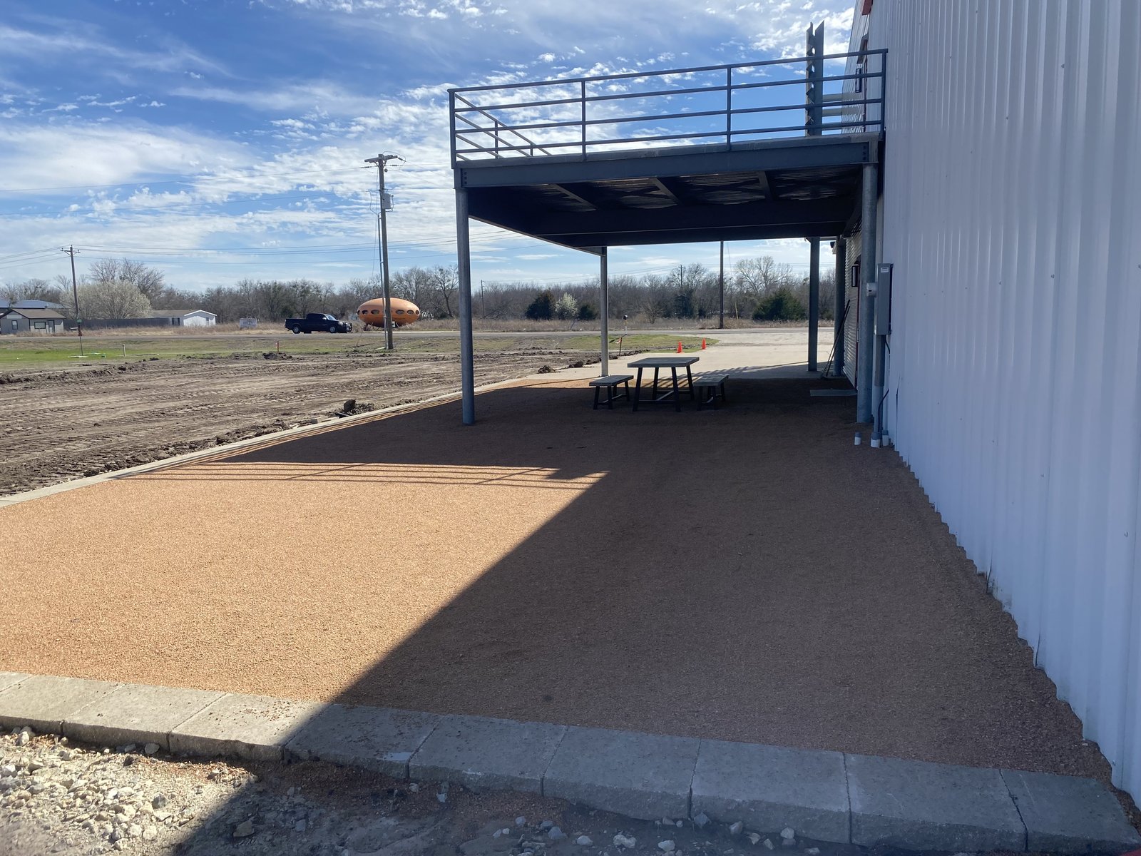 Gravel patio under a steel deck on a white metal building