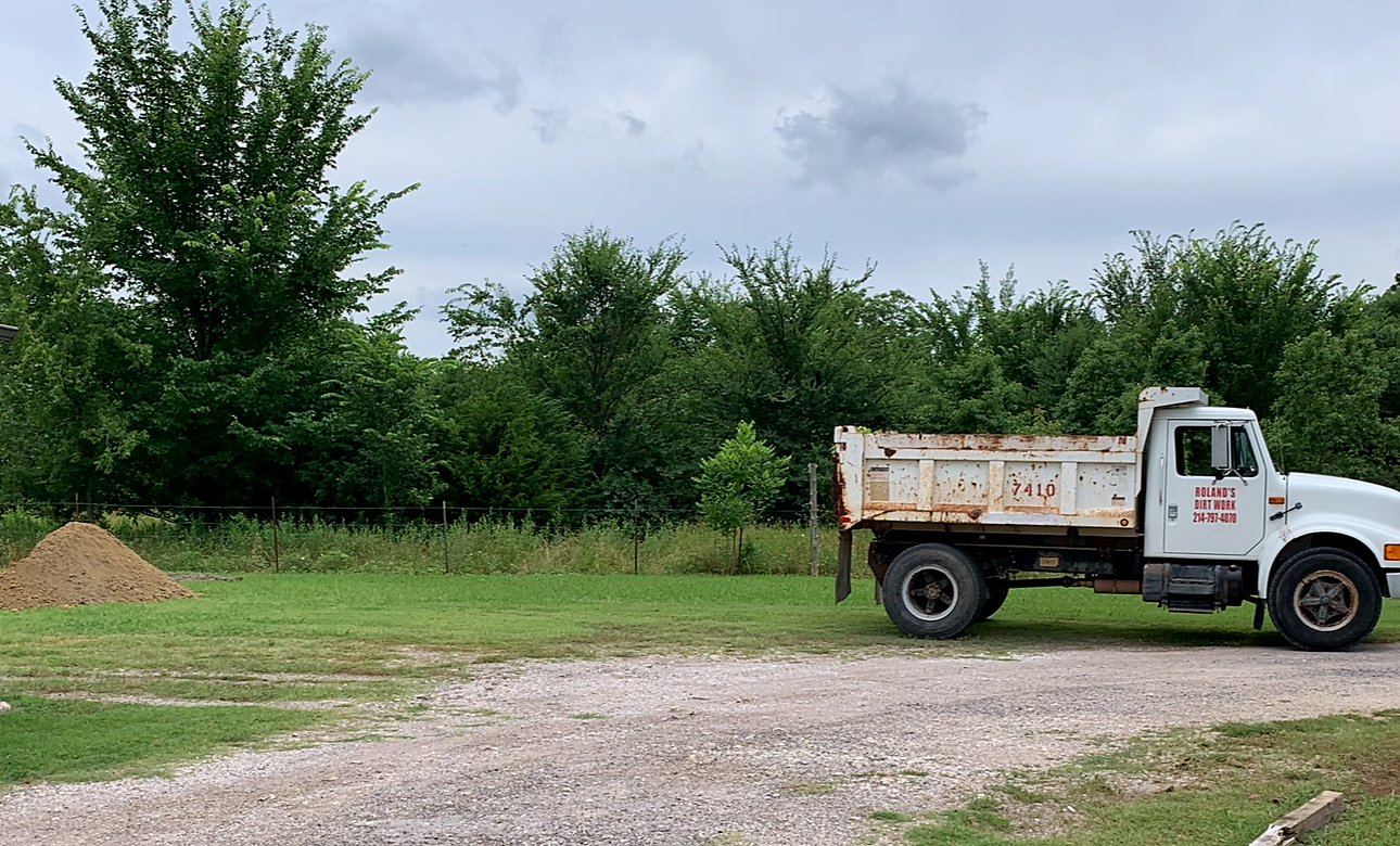 White dump truck with Roland's Dirt Work lettering and phone number