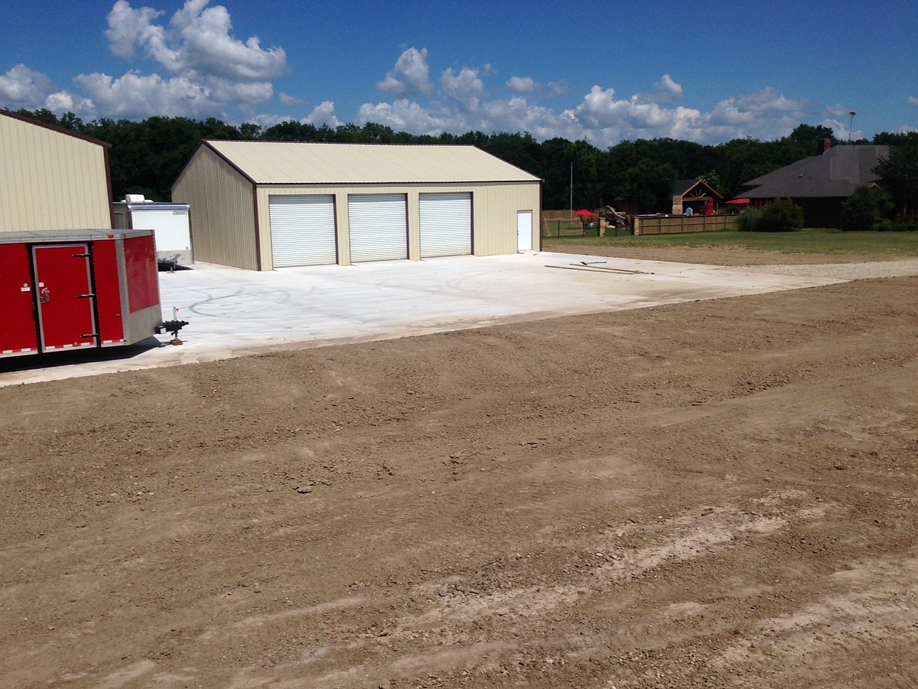 Graded dirt pad in front of a tan metal building