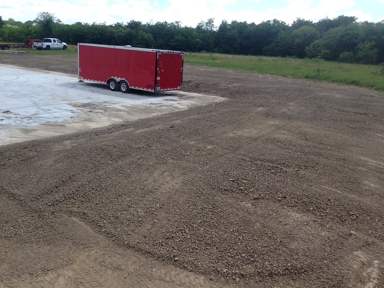 Graded berm and drainage area beside a red trailer on concrete